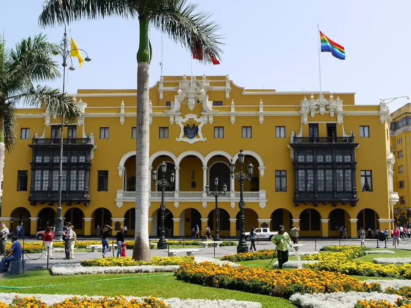Fachada amarilla del Palacio Municipal de Lima con balcones de madera y jardines